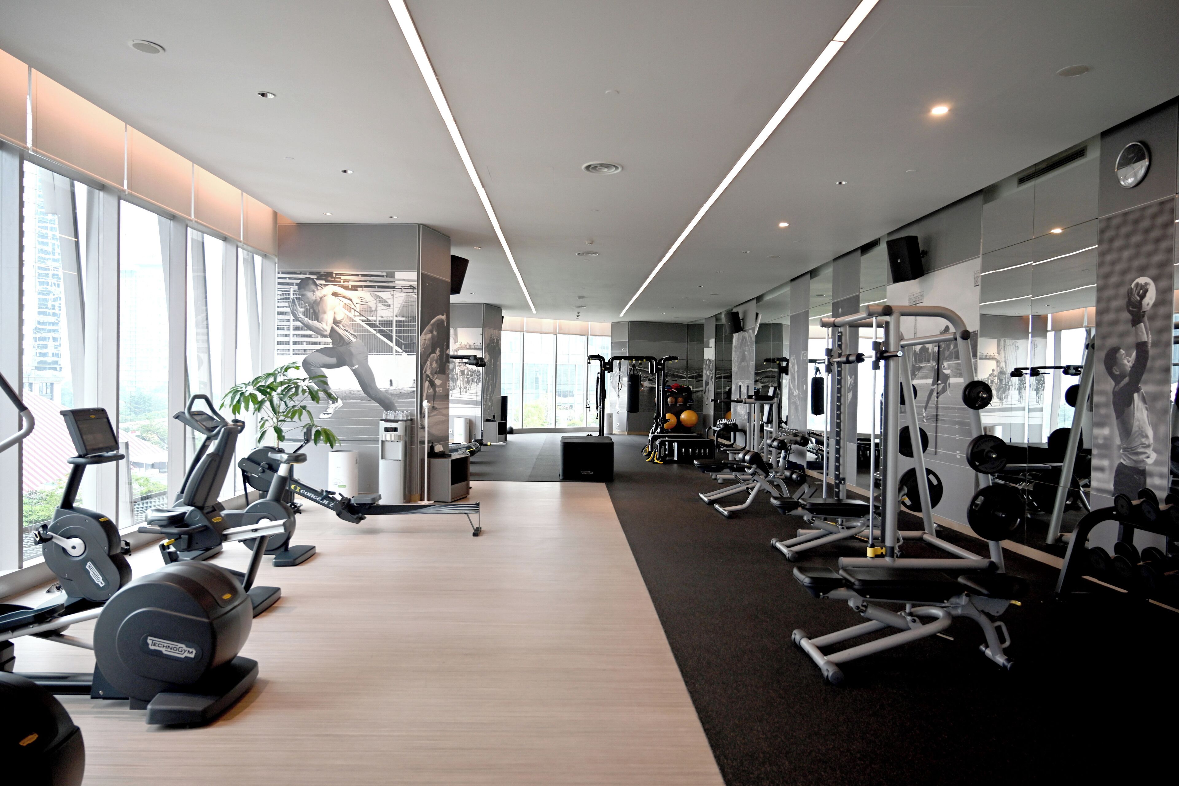 Un gimnasio moderno con máquinas de cardio, equipo de levantamiento de pesas y un espejo grande.