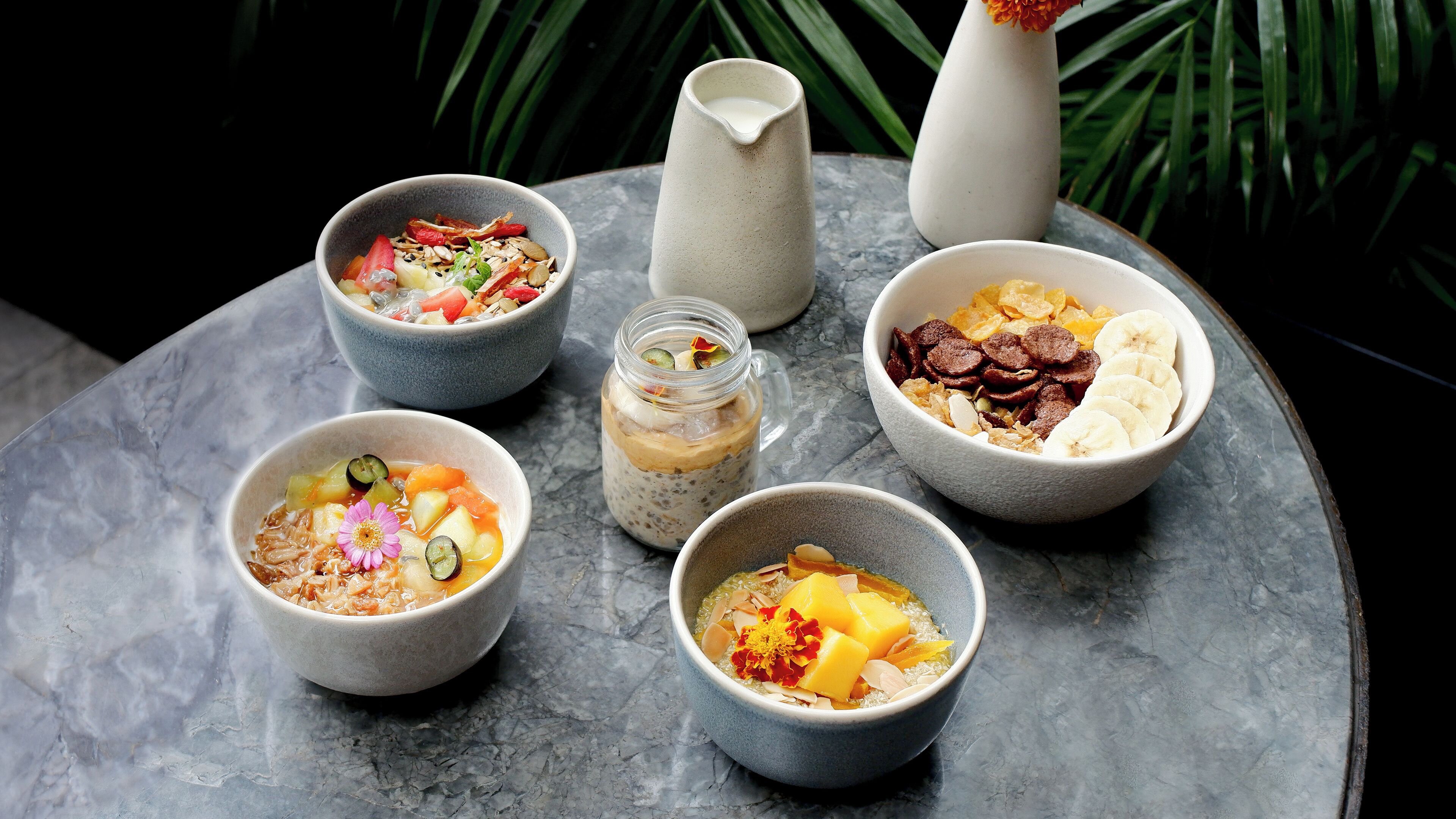 Six bowls of food on a marble table.