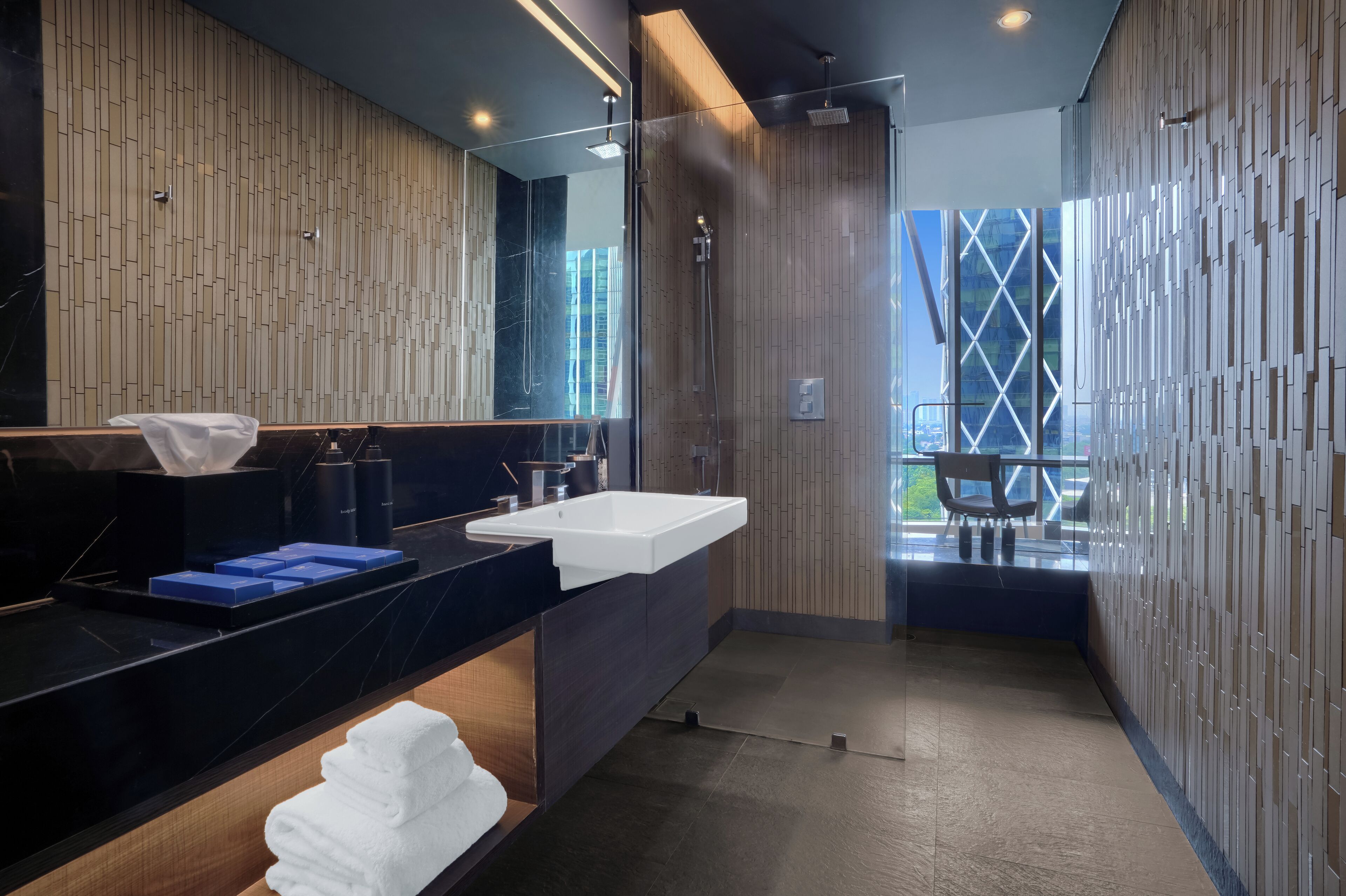 Une salle de bain moderne avec un grand miroir, deux lavabos et une douche.