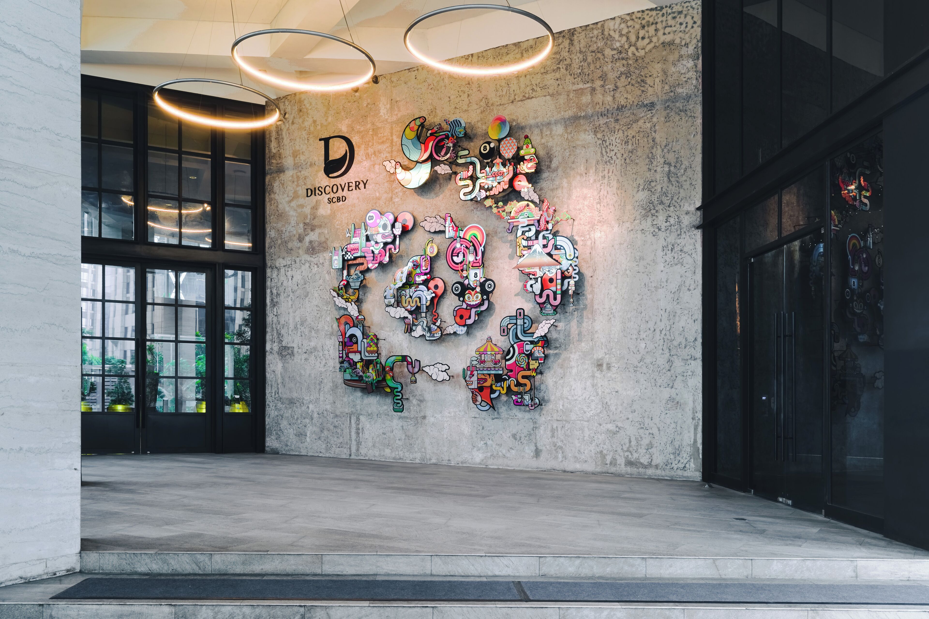 A modern interior with a concrete wall adorned with colorful, abstract art.