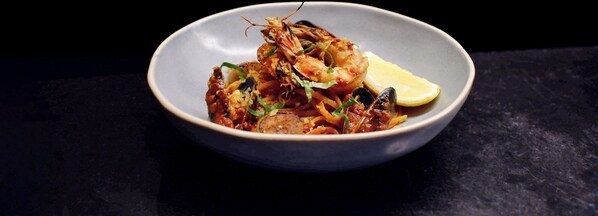 A bowl of seafood dish with a lemon wedge.