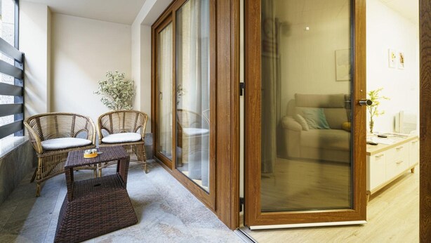 Una habitación con puerta corredera de vidrio, muebles de mimbre, una mesita y un sofá.