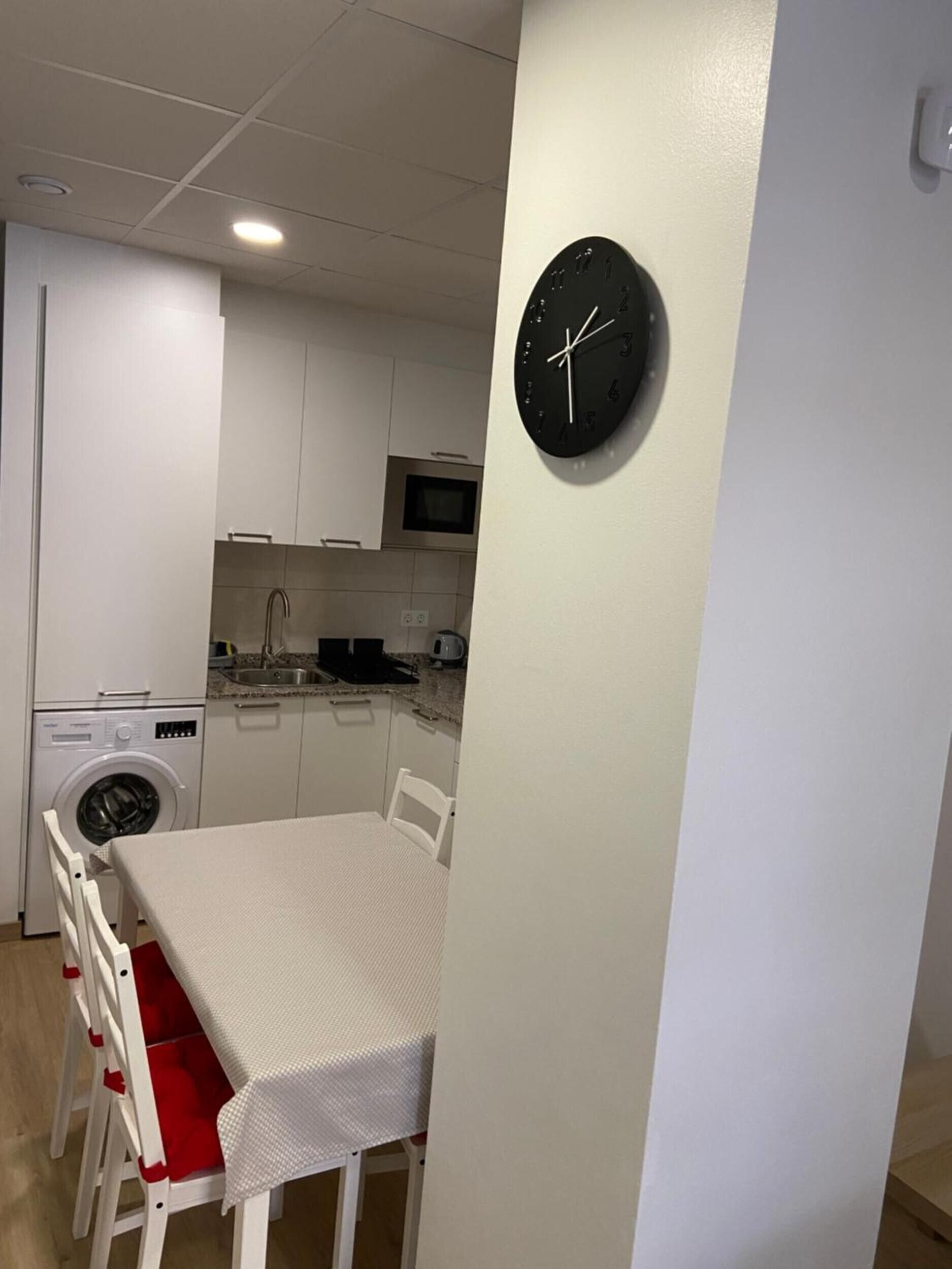 Una cocina compacta con microondas, lavamanos y lavadora.