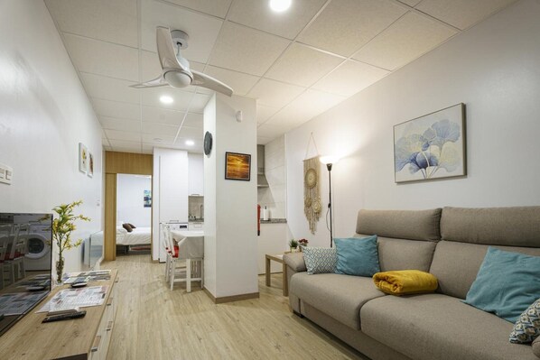 Una sala de estar moderna con un sofá, una mesa de centro, una mesa de comedor y una zona de cocina.