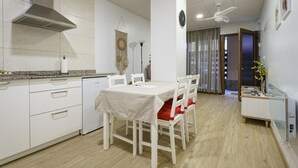 Una cocina moderna con armarios blancos, una campana extractora de acero inoxidable y un comedor con mesa y sillas.
