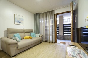 Una sala de estar con un sofá, un cuadro, una mesa con papeles y vistas a una escalera a través de una puerta.