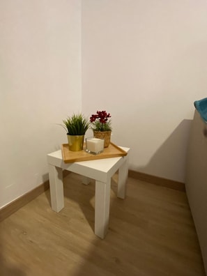 A small white table with a tray, a potted plant, and a candle.