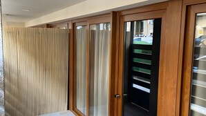 Un pasillo con piso de madera, un felpudo de cerámica y una puerta corrediza de vidrio, con vista a un estacionamiento.