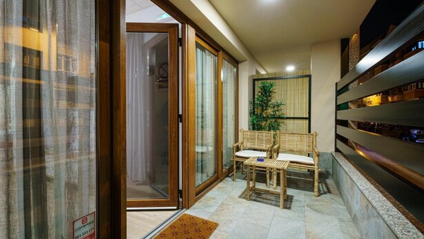 Un interior moderno con puertas de cristal correderas, una zona de estar con dos sillones, una planta en maceta y una estantería a lo largo de la pared.