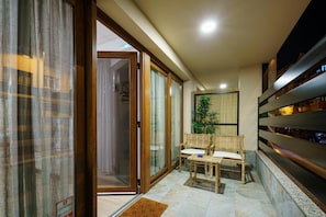 Ein modernes Interieur mit Schiebegläsern, einer Sitzecke mit zwei Stühlen, einem Topfpflanzen und einem Regal entlang der Wand.