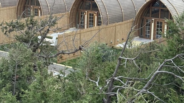 Una hilera de cabañas con forma de cúpula, armazón de madera y amplias ventanas, frente a un paisaje montañoso.