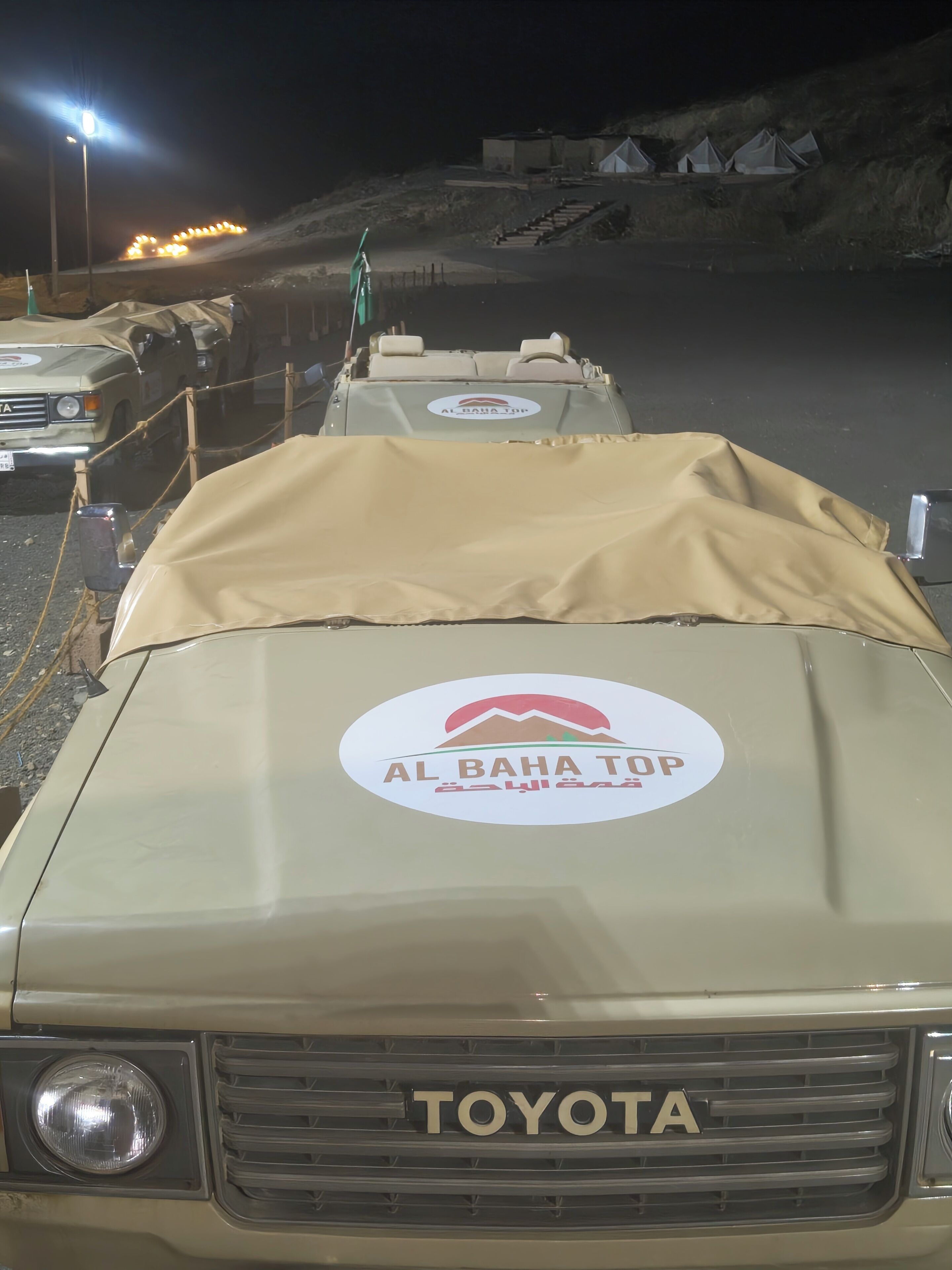 En Toyota-bil med ett täckt lastutrymme och en logotyp för Al Baha Top.