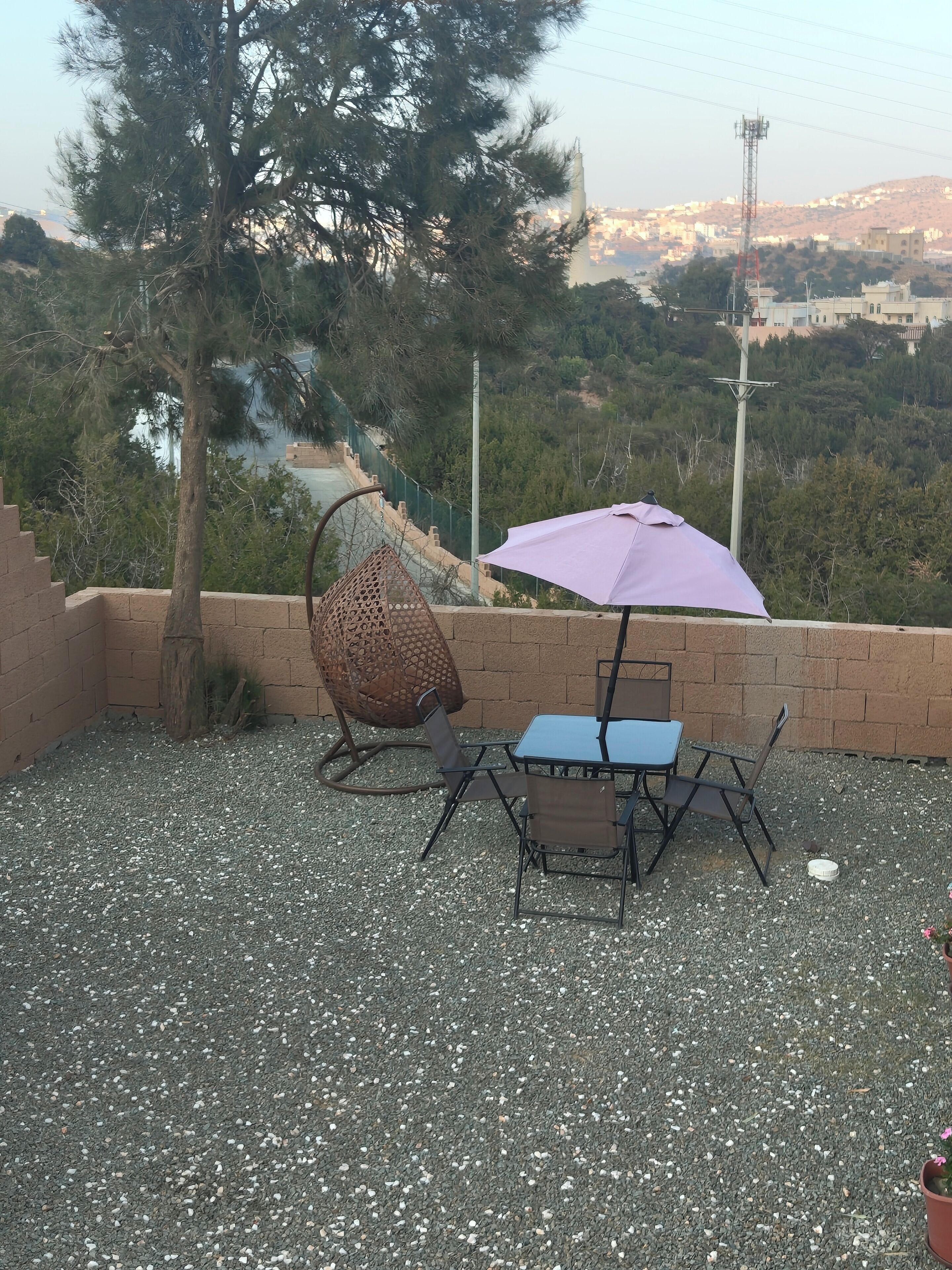 An outdoor seating area with a table and chairs, a hanging chair, and an umbrella.