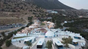 A modern resort with dome-shaped buildings, a central courtyard, and a mountainous backdrop.