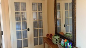 Ein Zimmer mit einer Doppeltür, einem Spiegel und einem Holzkonsolentisch mit Dekoration und Toilettenartikeln.