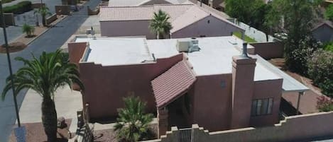 Un quartier résidentiel où les maisons se distinguent par leurs toits recouverts de tuiles rouges et leurs murs en stuc, le tout entouré de verdure et adossé à un paysage vallonné.