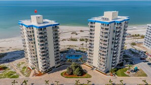 A high-rise hotel with multiple balconies, a central pool, and a beach view. - Estero Beach Tennis 1004c Direct Gulf Water Views (Fort Myers Beach)