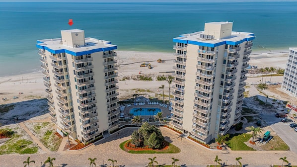 A high-rise hotel with multiple balconies, a central pool, and a beach view.