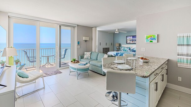 A modern apartment with a balcony, a dining area, and a kitchen. - Estero Beach Tennis 1004c Direct Gulf Water Views (Fort Myers Beach)