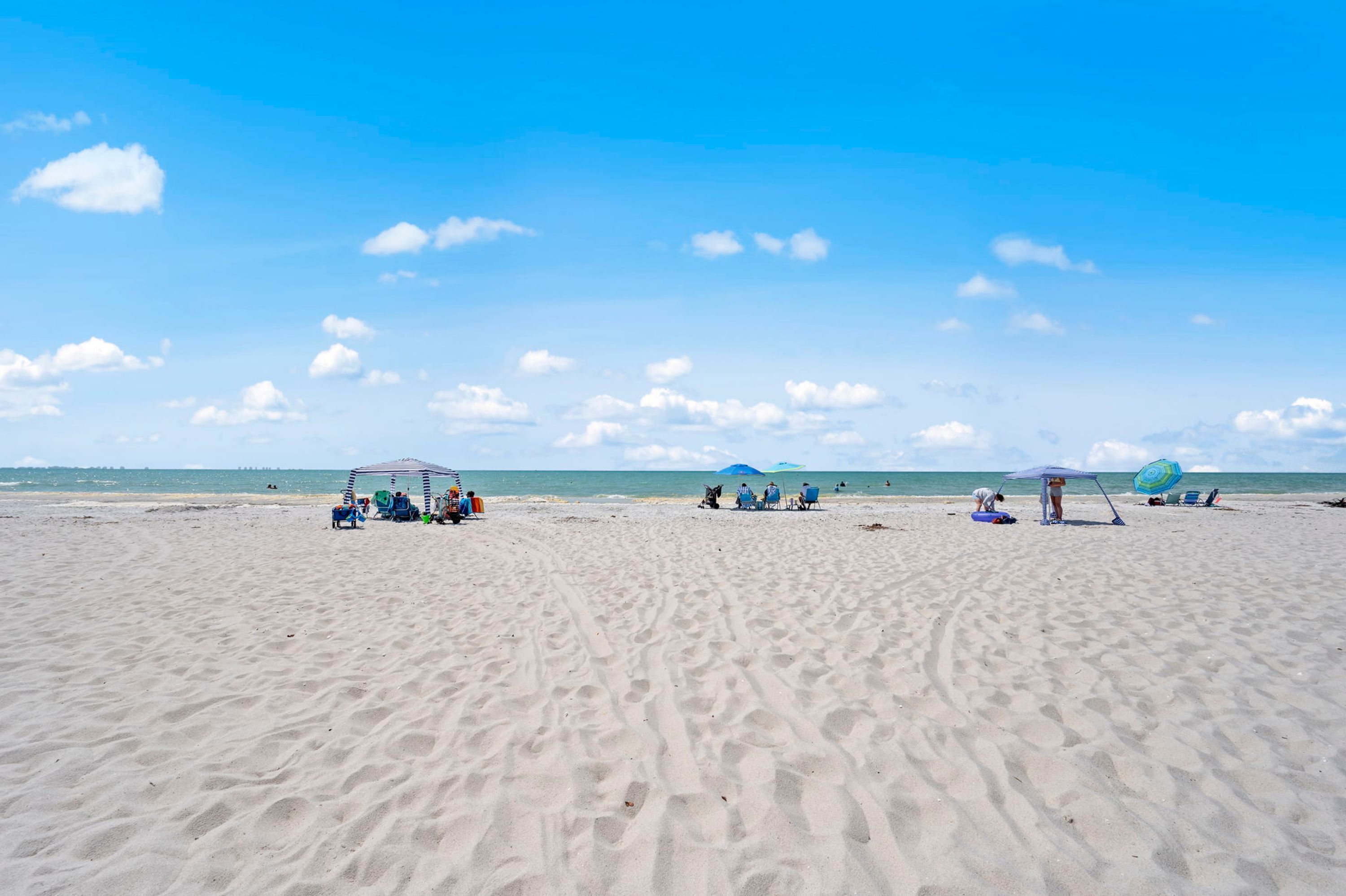 Een zandstrand met mensen en strandparasols.
