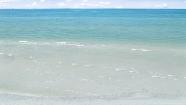 Una spiaggia con acque cristalline e una battigia sabbiosa.