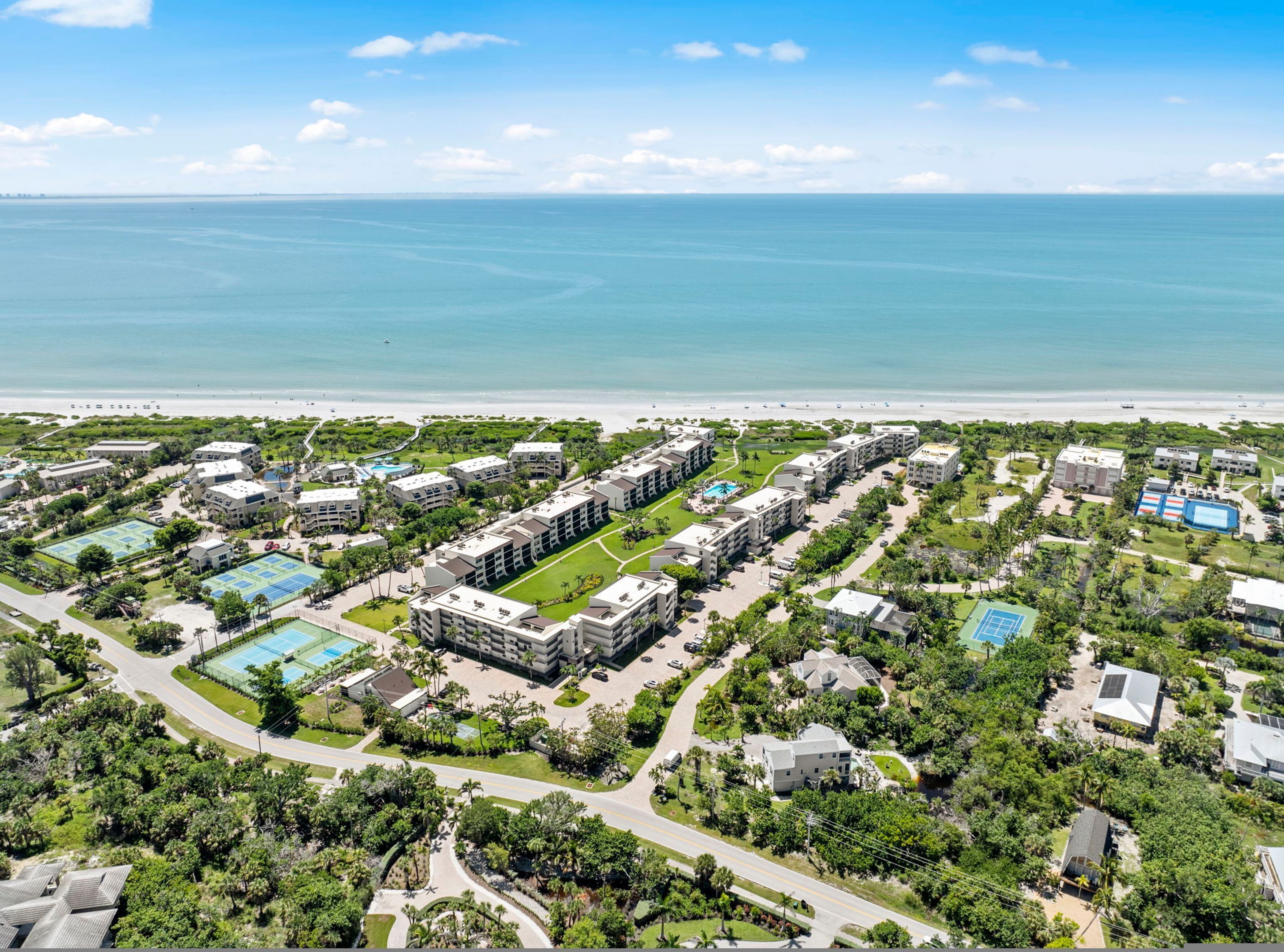 Eine Luftaufnahme eines Resorts mit mehreren Gebäuden, Pools und einem Strand.