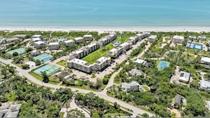 Vista aerea di un resort con diversi edifici, piscine e una spiaggia.