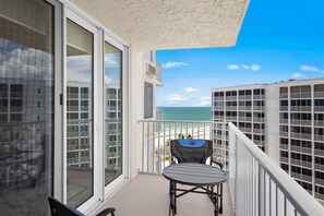 A balcony with a view of the beach, a chair, and a table. - New Luxury Estero Beach Tennis Club 708a (Fort Myers Beach)
