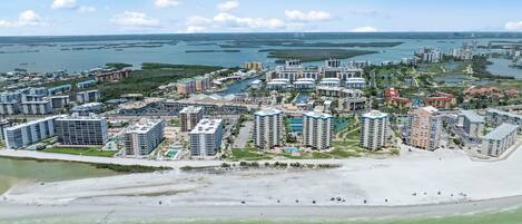 Una zona turística costera con varios edificios altos, una playa y un puerto deportivo.
