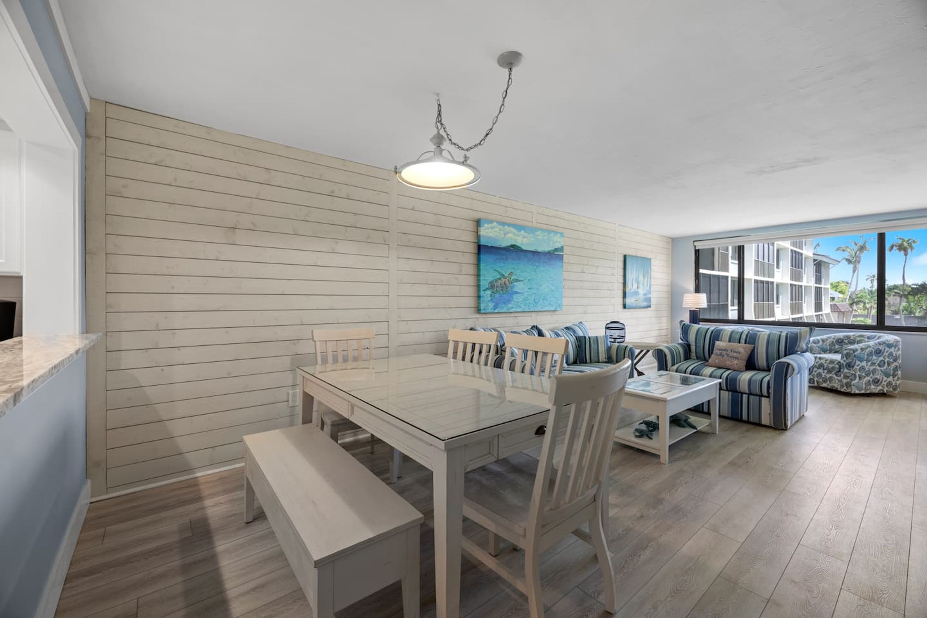 A spacious living area with a wooden wall, a dining table with chairs, a sofa, and a coffee table.