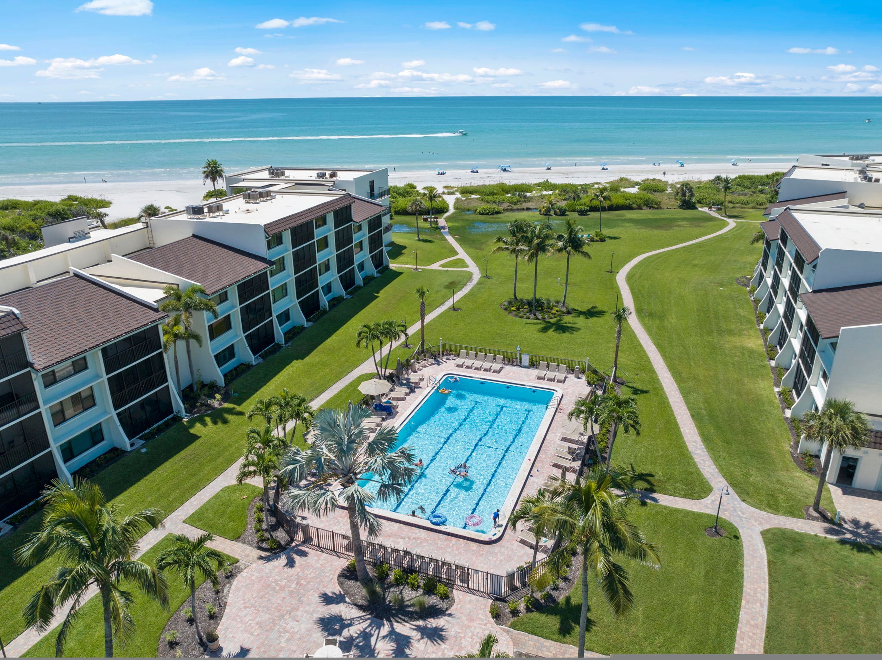 A hotel with a swimming pool, a beach, and a view of the ocean.