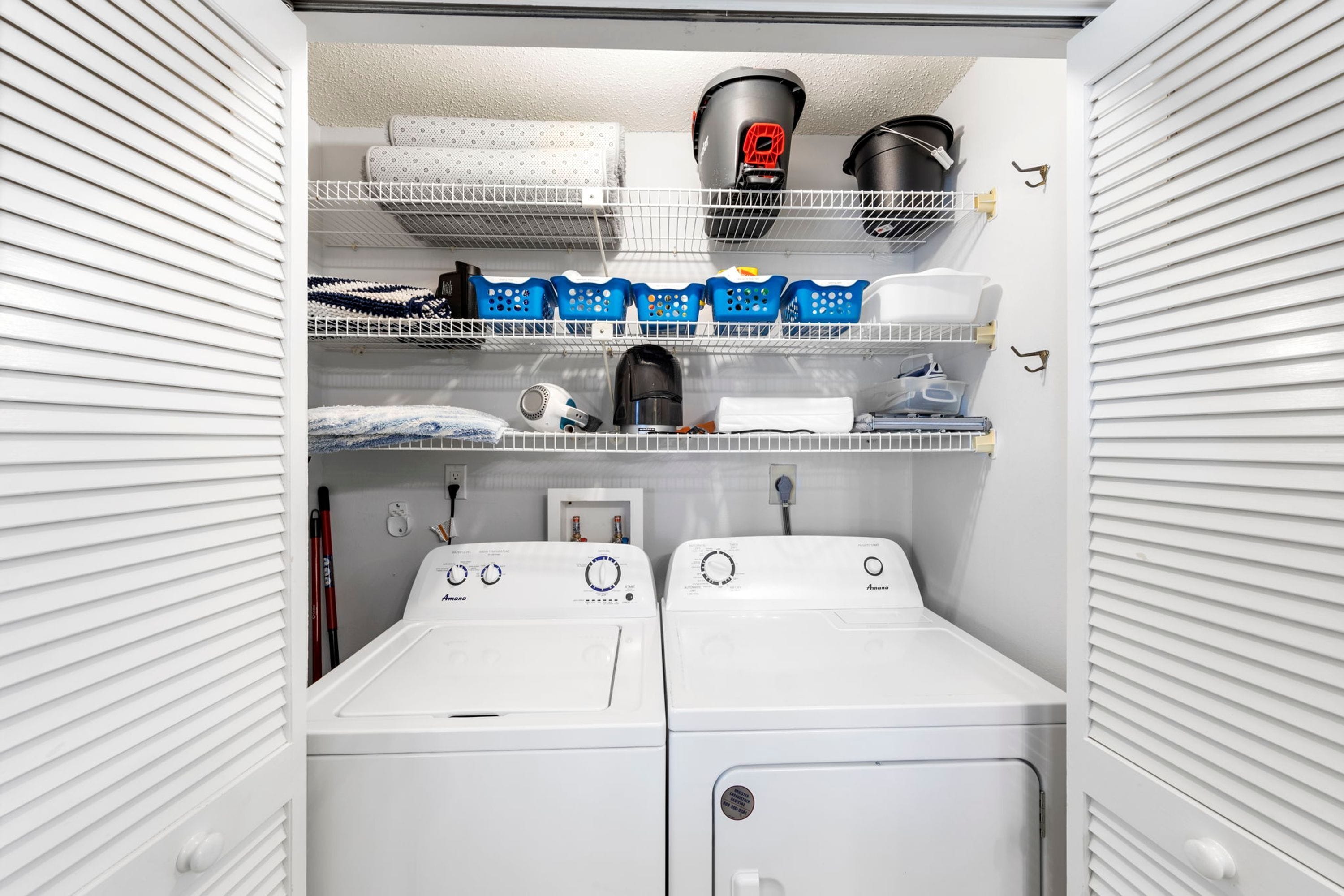 A laundry room with two washing machines, shelves with laundry baskets, and a hairdryer.
