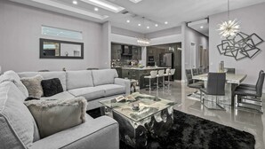 Ein modernes Wohnzimmer mit einem grauen Sofa, einem Glastisch und einem schwarzen Teppich.