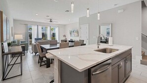 A modern kitchen with a large island, stainless steel appliances, and pendant lighting.