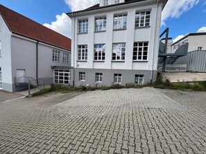 A building with a paved courtyard, multiple windows, and a staircase leading to an upper level. - Apartment '1' with Shared Terrace and Wi-Fi (Albstadt)