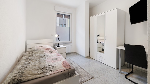 A bedroom with a bed, a desk, a chair, a wardrobe, and a TV. - Room '4' with Shared Terrace and Wi-Fi (Albstadt)