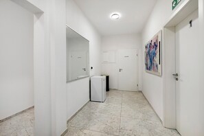 A hallway with white walls, a refrigerator, a trash bin, and a door with a number. - Room '4' with Shared Terrace and Wi-Fi (Albstadt)