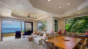 Uma sala de estar espaçosa com uma grande janela com vista para o oceano, um espaço de estar aconchegante e uma mesa de jantar.
