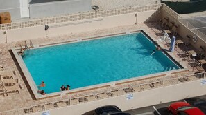 A rectangular swimming pool with a tiled deck surrounding it, equipped with lounge chairs and a lifeguard stand. - #402 Southpoint 2/2 Oceanfront Traffic Free Beach (Ponce Inlet)