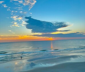 A beach scene with a sunset, calm sea, and a few people in the distance. - 402 Southpoint in Ponce Inlet, FL (Ponce Inlet)