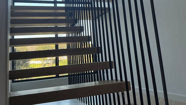 Eine moderne Treppe mit Holzoptik und schwarzen Metallgeländern.