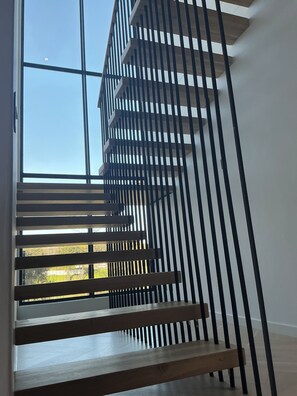 A modern staircase with a wooden finish and black metal railings. - Enjoy a relaxing getaway in our new luxury apartment, central to most amenities (Cape Town)