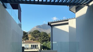 Ein moderner Balkon mit Korbmöbeln und freiem Blick auf die Berge im Hintergrund.