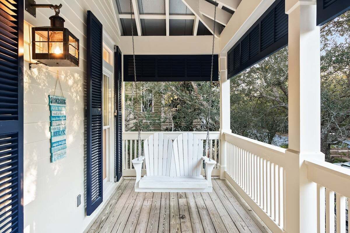 A porch with a white swing, black shutters, and a hanging lantern.