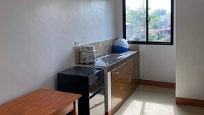 A compact kitchen with a dining table, a built-in oven, and a window with a view of greenery and buildings.