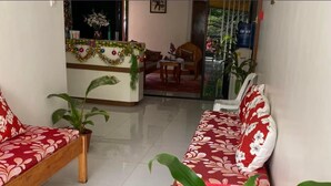A reception area with a sofa set, a plant, and a decorative garland.