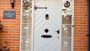 A white door with a diamond pattern, a black metal handle, and a black metal latch. There is a sign above the door that reads "31 Harbour View". - Blakeney. Harbour View (Blakeney)
