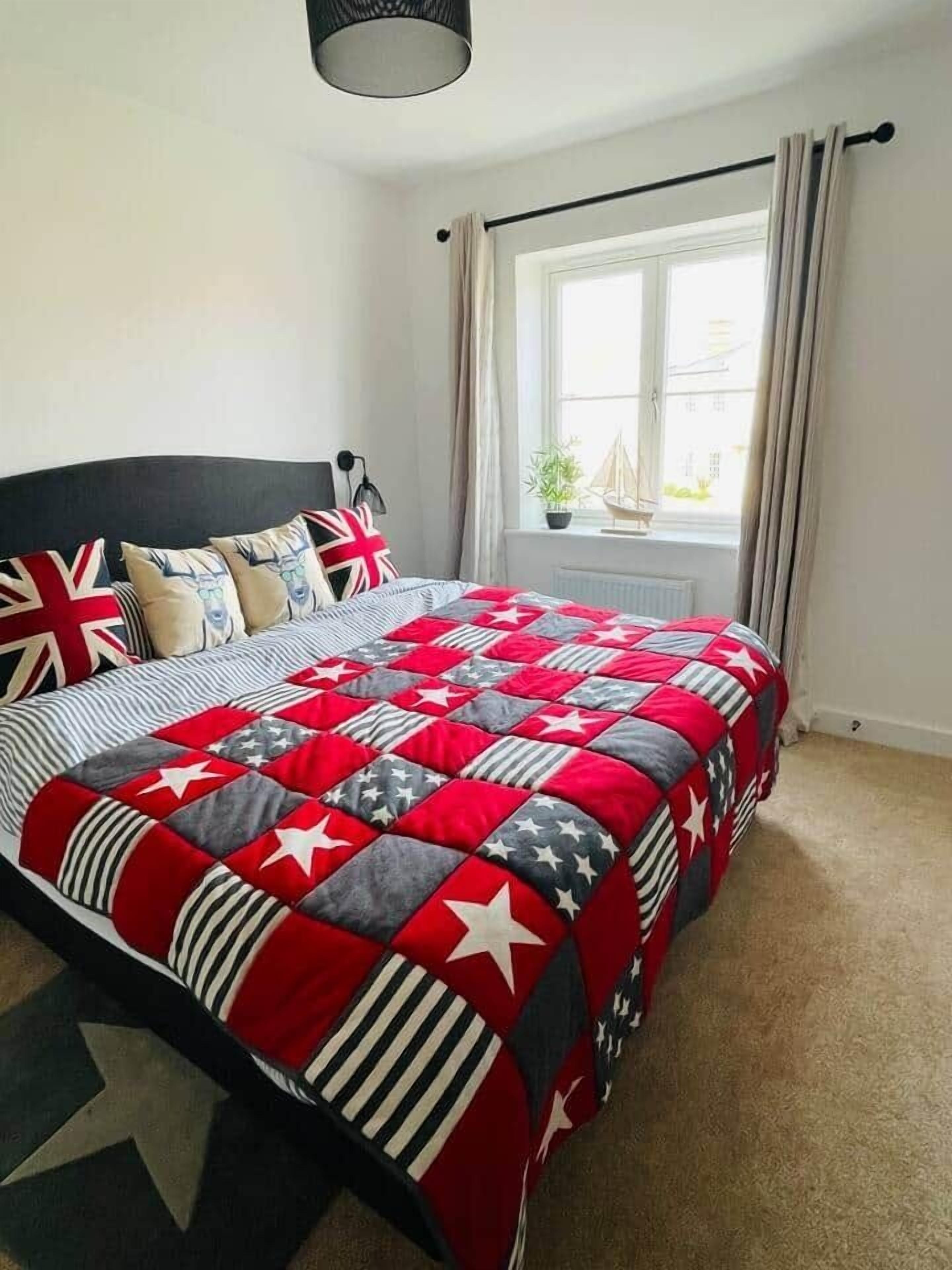 Een slaapkamer met een bed, een raam met gordijnen, een plant op de vensterbank en een radiator.