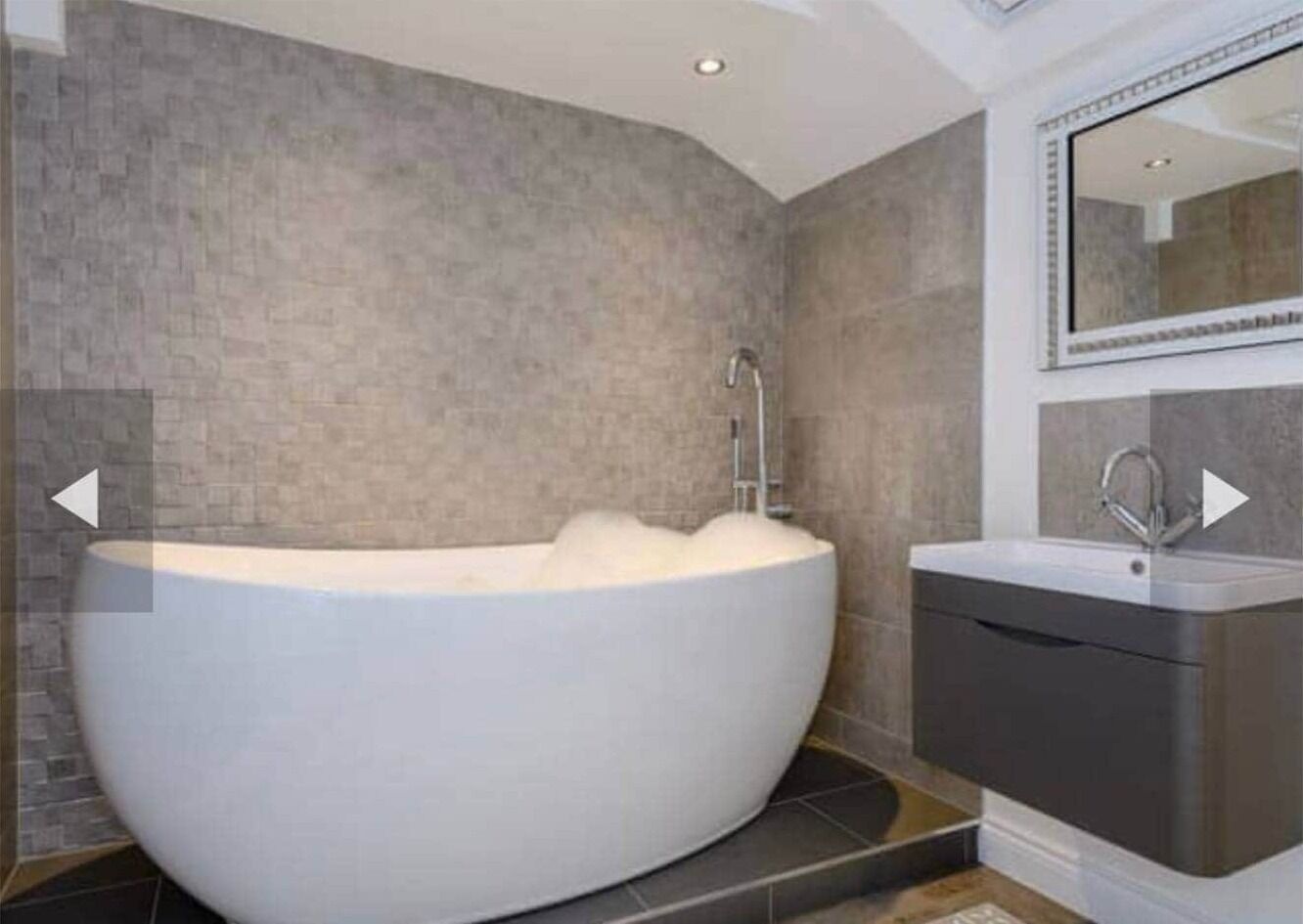 A modern bathroom with a freestanding bathtub, a sink, and a mirror.