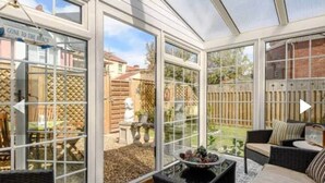 A conservatory with glass doors, wicker furniture, and a view of a backyard. - West Cottage. Central, spacious, 2 mins to beach. (Cromer)
